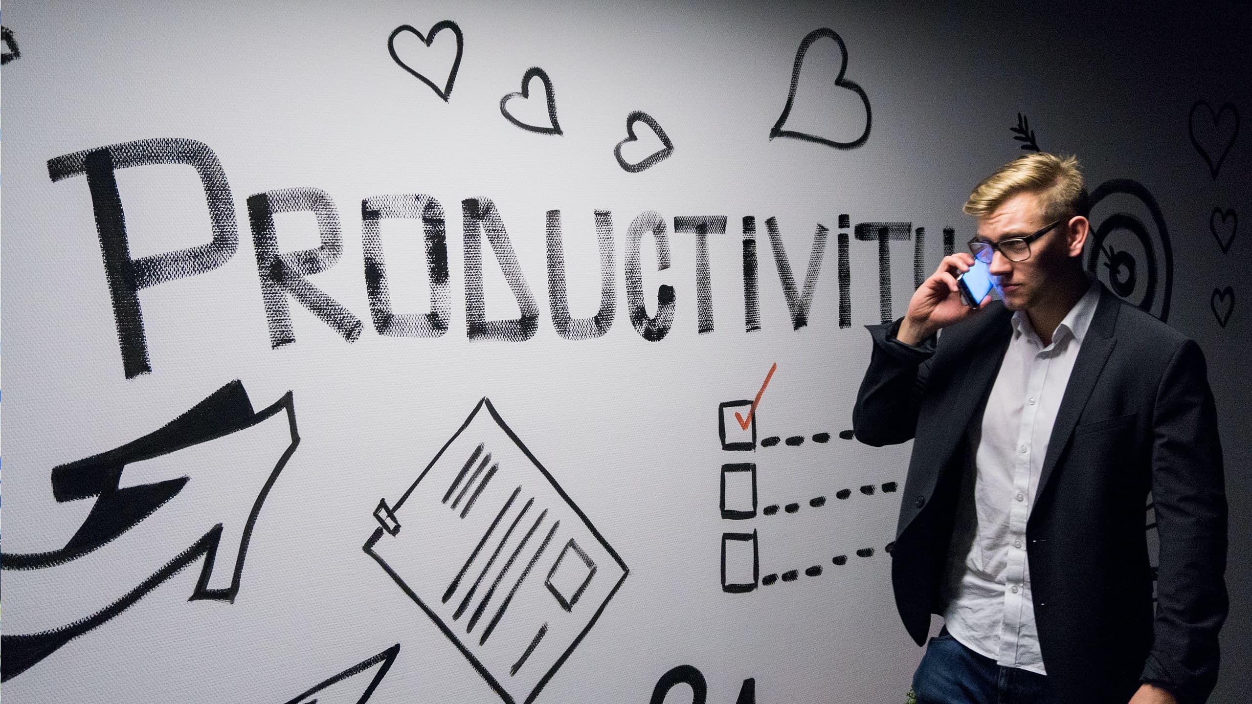 Man on phone walking by productivity sign