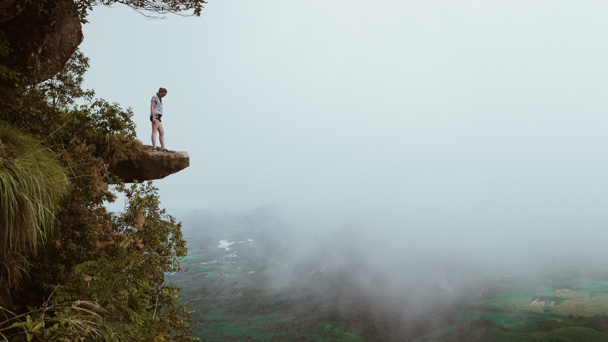 Woman standing on mountain looking into fog