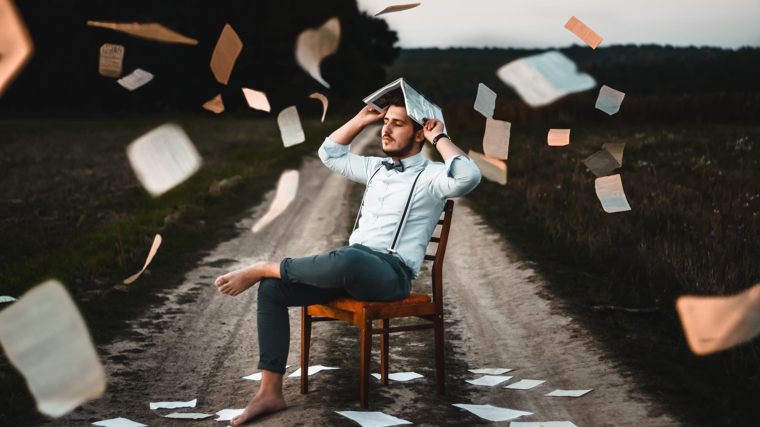 Man sitting with books flying around him