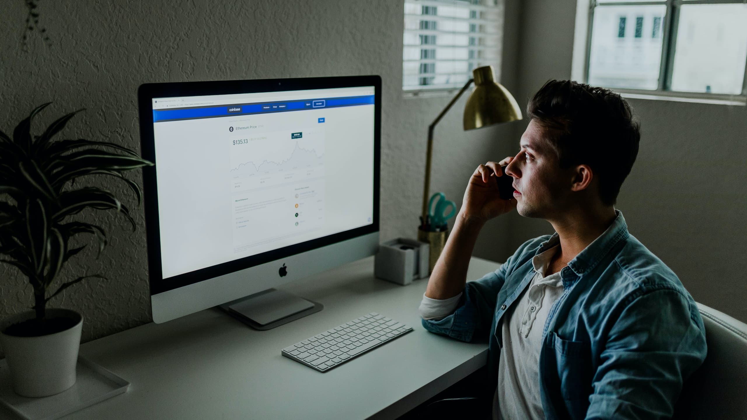 Man staring at desktop computer while on phone